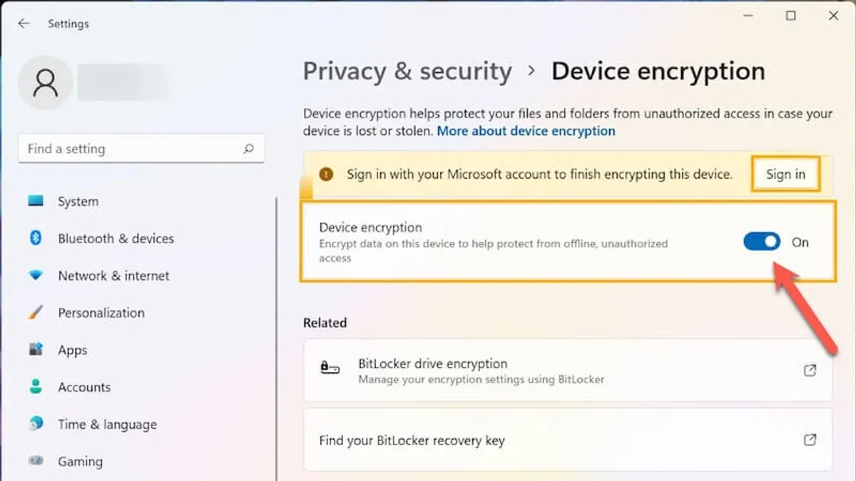 Person enabling device encryption Windows 11 Home on a laptop screen